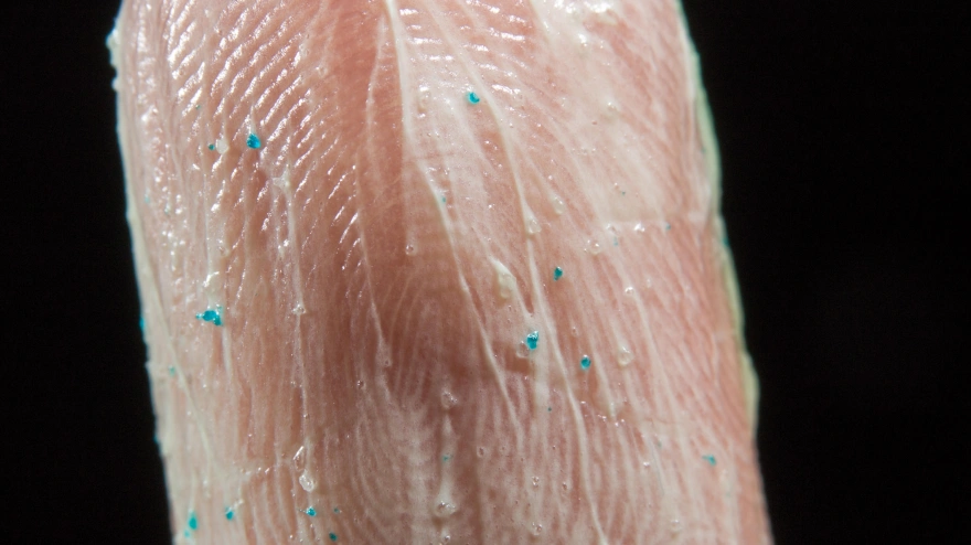 Primer plano de microperlas de un exfoliante facial en la punta de un dedo