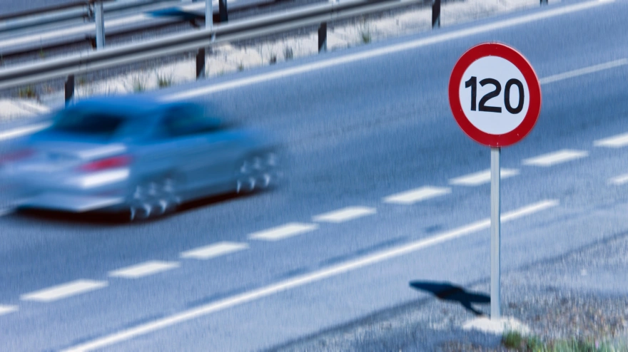 Señal de velocidad máxima a 120 kilómetros hora y un coche