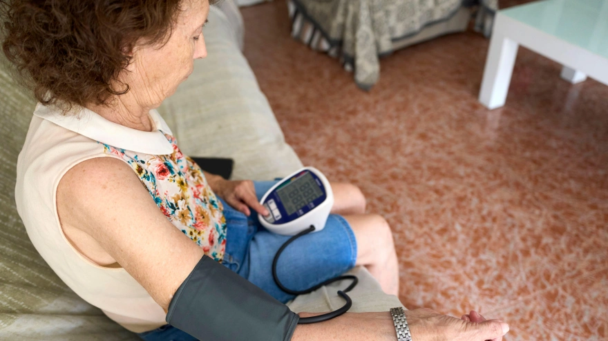 Mujer jubilada midiendo su presión arterial en casa