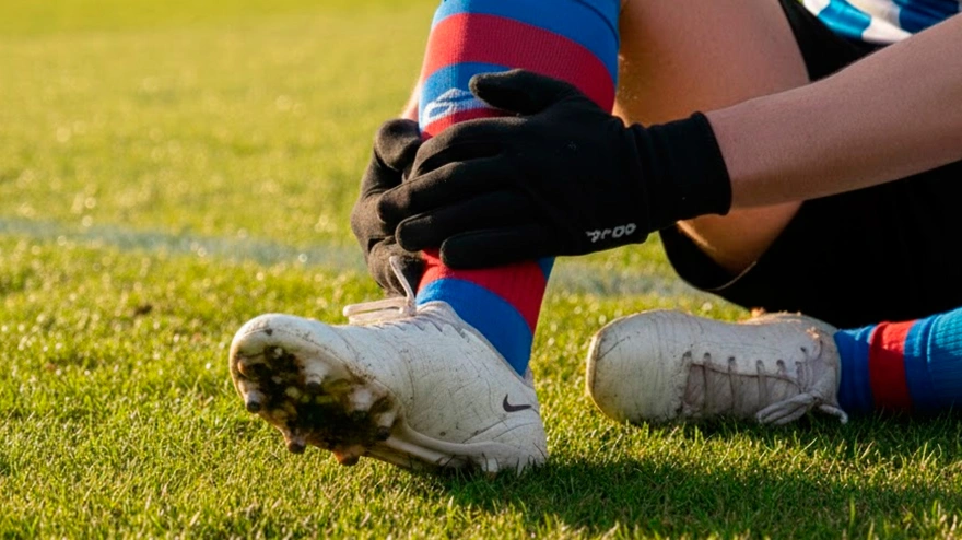 Un futbolista se echa la mano al tobillo tras sufrir una lesión