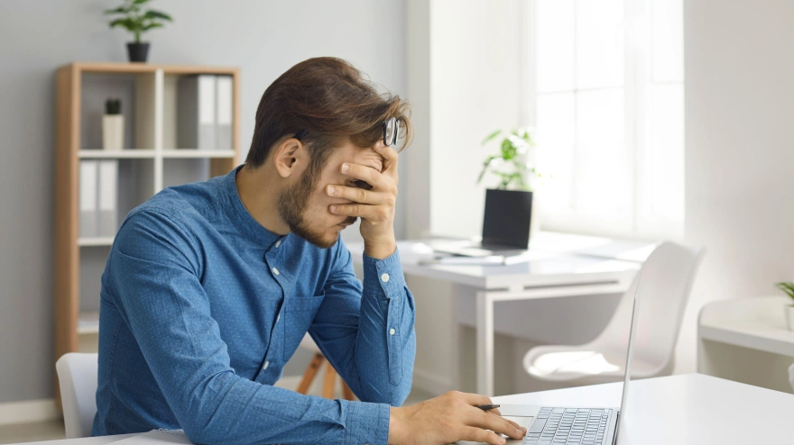 Un joven empleado estresado y agotado sufre un agotamiento en el trabajo en la oficina