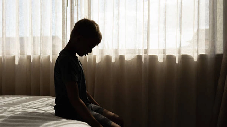 Sad little boy crying sitting at home in bed