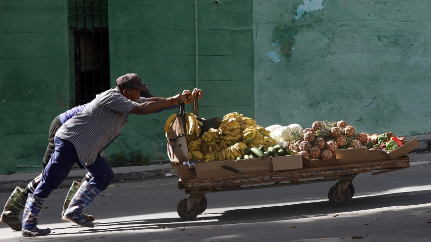 Personas empujan una carretilla con frutas por una calle este lunes, en La Habana, (Cuba)