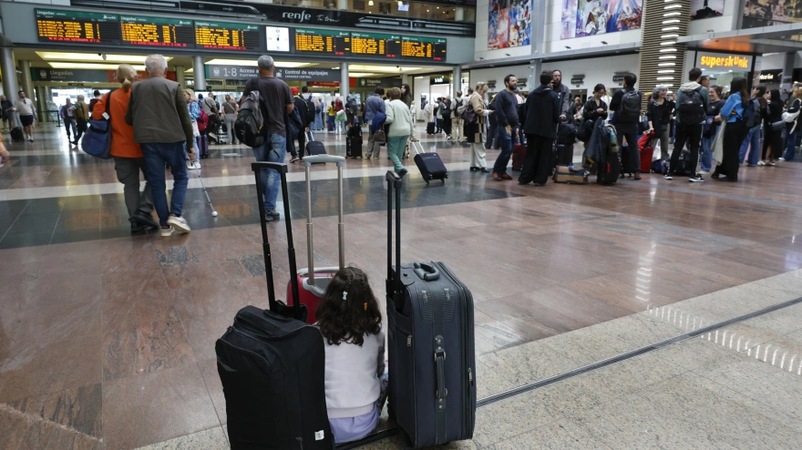 Una niña aguarda junto al equipaje de su familia en la Estación María Zambrano de Málaga