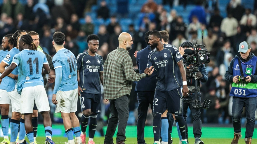 Pep Guardiola y Antonio Rüdiger se saludan tras el partido sobre el césped.