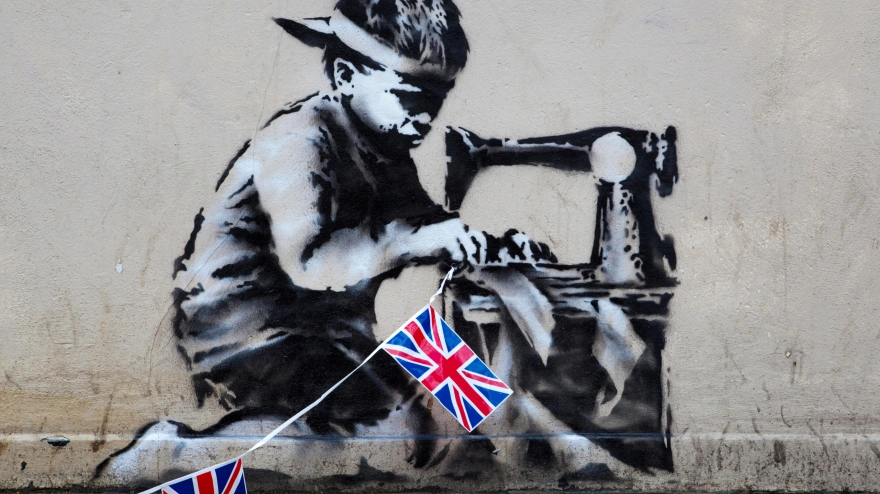 D3PBWK A work from Graffiti Artist Banksy that appeared on a wall of the retailer Poundland shortly before the start of the 2012 Olympic games in the city has been remove and placed on sale on the American Auction site 'Live Auctioneers' with a guide price of $500,000 - $700,000. The piece depicts an Asian child stitching together Union Jack Bunting. The work was said to be Banksy's commentary on child labour in a year that saw both the Queen's Diamond Jubilee celebrations and the Olimpic games in the Capital.http://www.liveauctioneers.com/item/15778020_banksy-slave-labor-bunting-boy-london-2012