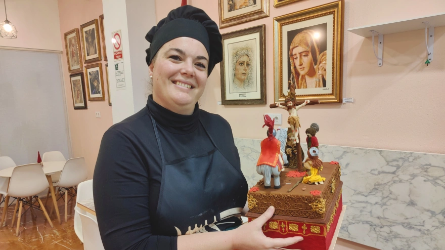 María del Pilar, repostera cofrade, sostiene un pastel que ha elaborado con la forma de un paso de la Hermandad de la Lanzada de Huelva.