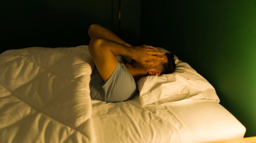 Problemas en el sueño, hombre con manos en la cara tumbado
