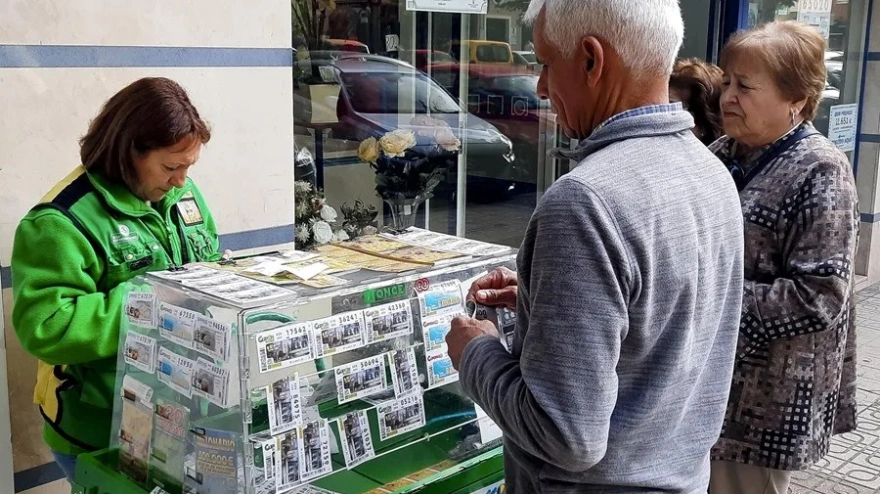 Una vendedora de la ONCE atendiendo a unos clientes