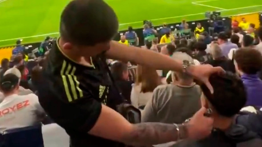 El joven peluquero trabaja en las gradas del Bernabéu, mientras el partido sigue a su alrededor.