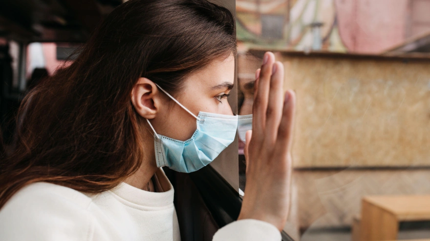 Una joven hipocondríaca mira desde la ventana durante la pandemia