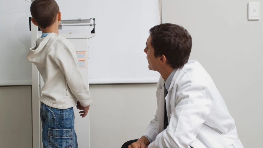 Un pediatra toma la altura a un niño, imagen de recurso