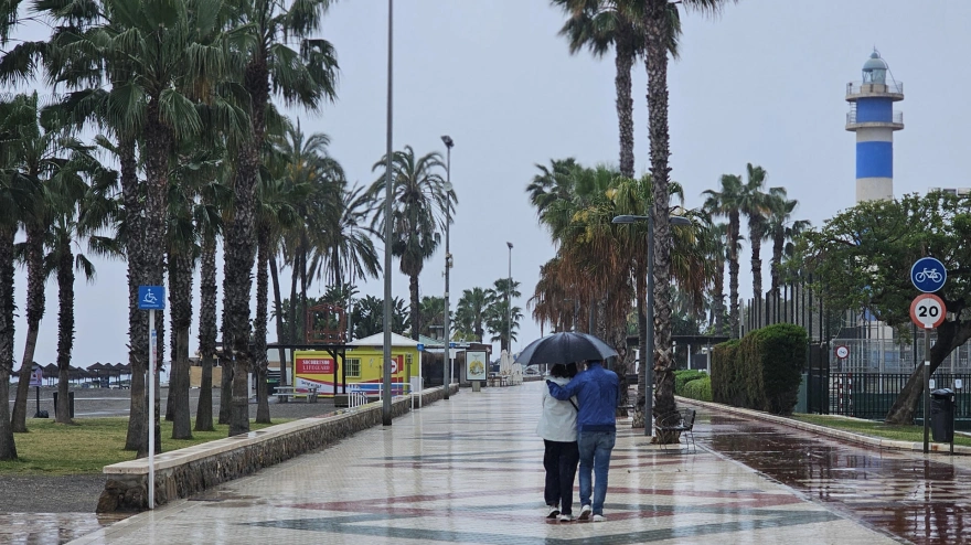 Varias personas pasean bajo la lluvia por el paseo marítimo de Torre del Mar, en Vélez-Málaga