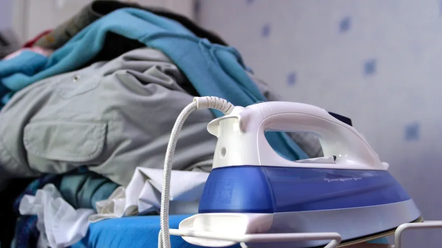 Montaña de ropa para planchar sobre la tabla de planchar con la plancha