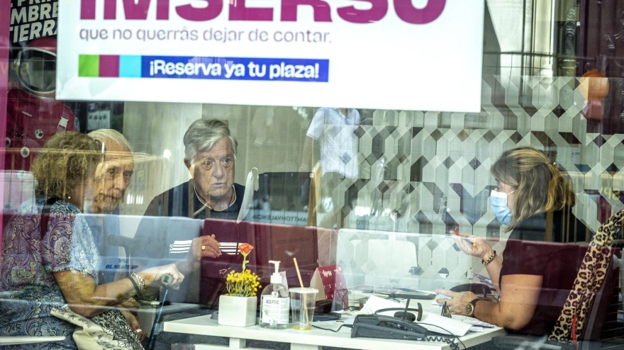 Jubiladas en una agencia de viajes donde se anuncia viajes del Imserso