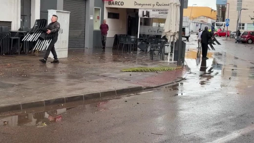 Vecinos limpiando su local cerca de la plaza de Extremadura